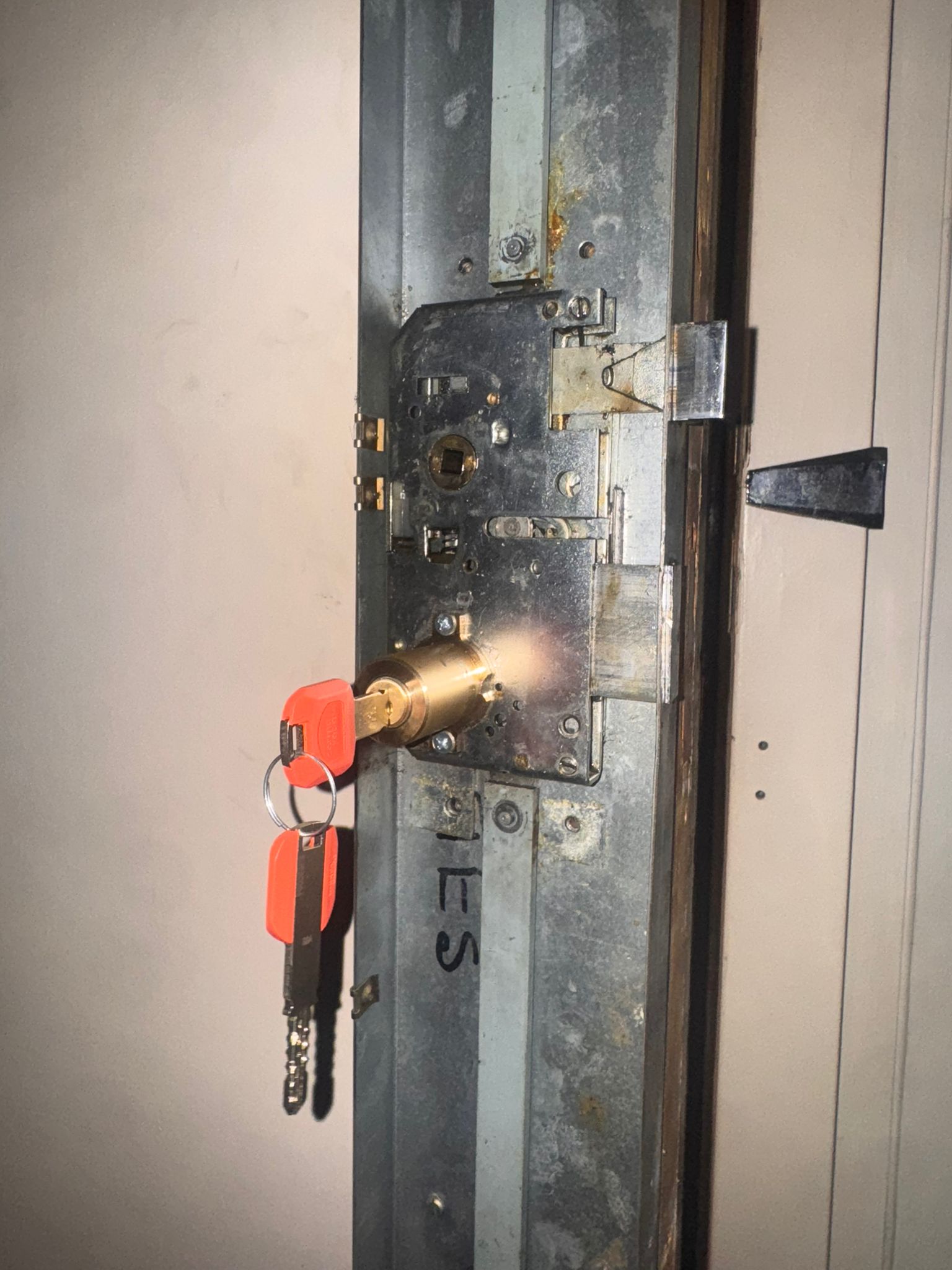 Cerradura multipunto de puerta acorazada con bombín nuevo instalado y llaves en llavero rojo, vista de detalle