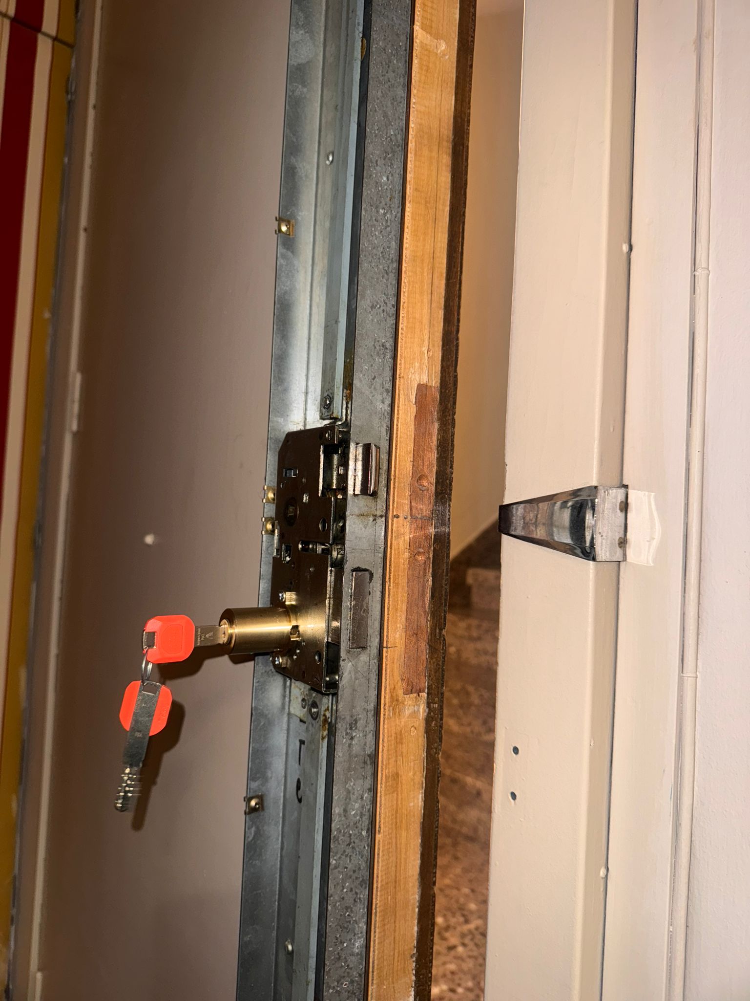Cerradura multipunto de seguridad vista desde el canto de puerta acorazada con bombín dorado y llaves puestas