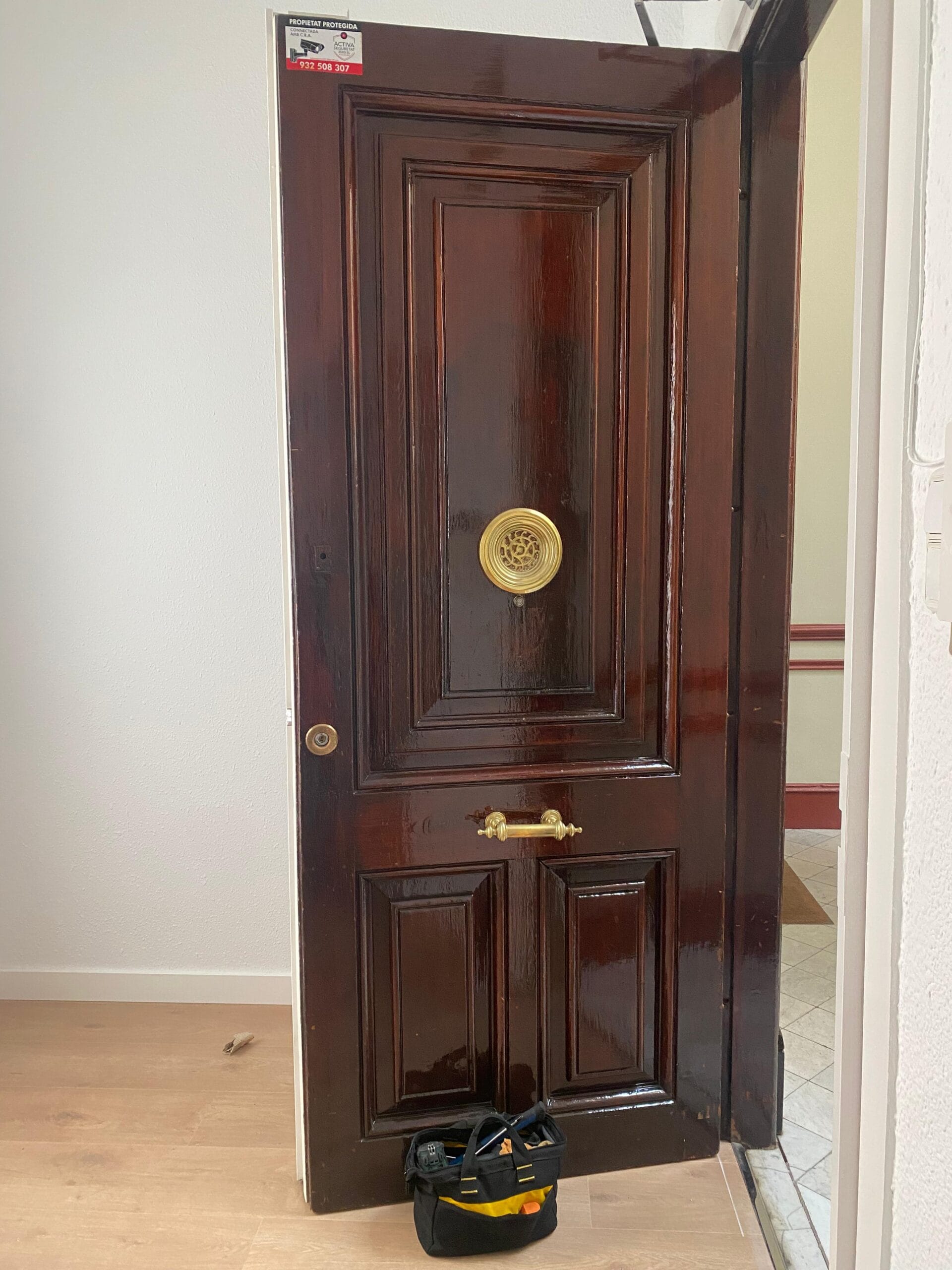 Puerta de madera clásica con herrajes dorados y bombín
